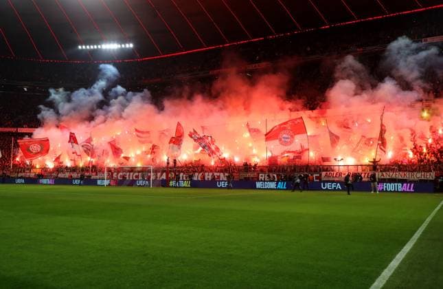 Football, Men, Champions League, Season 2024 2025, FC Bayern Munich Bayer 04 Leverkusen, Round of 16 first leg, Allianz Arena Pyro, Bengalo, Fire in the south curve at the start of the match, Fans, Flags