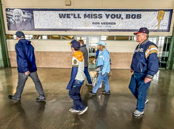 Fans walk past a tribute banner signed by fams for former Milwaukee Brewers catcher and broadcast announcer Bob Uecker before the start of the MLB, Baseball Herren, USA baseball game between the Kansas City Royals and the Milwaukee Brewers at American Family Field in Milwaukee, Wisconsin on Monday, March 31, 2025. Uecker died at age 90 on January 16, 2025 at his home in Menomonee Falls, Wisconsin. The game is the Brewers 2025 season home opener.  MIL202503318 TANNENxMAURY