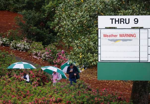 Patrons tour the coarse holding umbrellas in the rain during a practice round with a weather warning in place before it is announced that play is suspended due to an approaching thunder storm with lightning in the area at the Masters Tournament at Augusta National Golf Club in Augusta, Georgia on Monday, April 7, 2025.  AUG20250407105 JOHNxANGELILLO