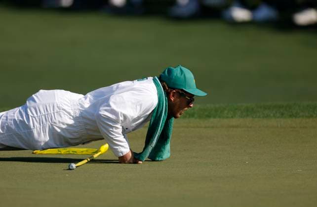 Patrick Reed s caddie Kessler Karain lies down to read the seventh green during the first round of the Masters golf tournament at Augusta National Golf Club in Augusta, Georgia on Thursday, April 10, 2025.  AUG20250410543 JOHNxANGELILLO