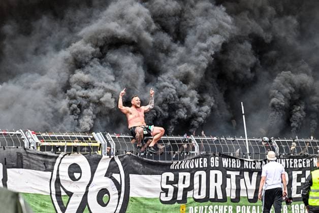 Bilder des Jahres 2025, Sport 05 Mai Sport Themen der Woche KW18 Sport Bilder des Tages GER, 2. BL, SSV Ulm 1846 vs Hannover 96 03.05.2025, Donaustadion, Ulm, GER, 2. BL, SSV Ulm 1846 vs Hannover 96, im Bild Ultra aus Hannover sitzt auf dem Zaun, dahinter ziehen Rauchschwaden von Pyrotechnik und Bengalos *** GER, 2 BL, SSV Ulm 1846 vs Hannover 96 03 05 2025, Donaustadion, Ulm, GER, 2 BL, SSV Ulm 1846 vs Hannover 96, in the picture Ultra from Hannover sits on the fence, behind him clouds of smoke from pyrotechnics and Bengalos are drifting nordphotoxGmbHx xHafner nph00200
