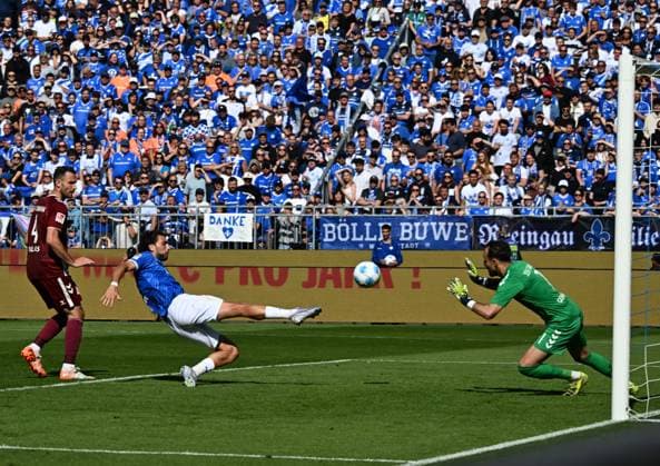 18 05 2025, xsltx, Soccer 2 Bundesliga, SV Darmstadt 98 Jahn Regensburg v l With an artistic straddle Fraser Hornby SV Darmstadt 98 spikes the ball into the net for 2 1 Li Florian Ballas SSV Jahn Regensburg , re Felix Gebhardt SSV Jahn Regensburg DFL DFB REGULATIONS PROHIBIT ANY USE OF PHOTOGRAPHS as IMAGE SEQUENCES and or QUASI VIDEO