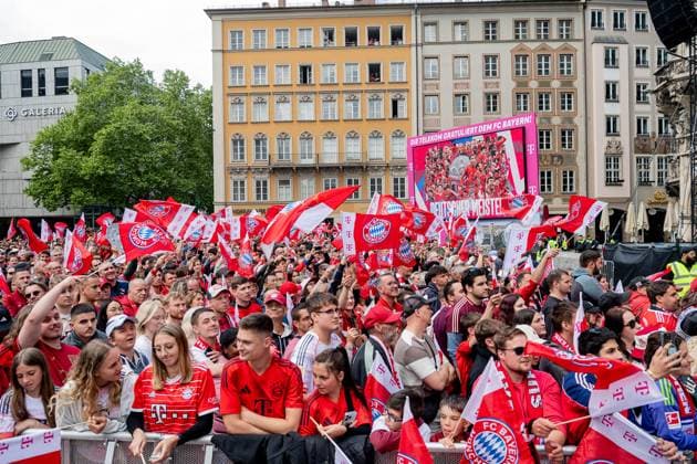 The fans wait excitedly for the teams on Marienplatz Behind them is a poster with the inscription Die Telekom congratulates FC Bayern Deutscher Meister Reception and championship ceremony FC Bayern Muenchen Maenner und Frauen, Fußball, Bundesliga, Saison 2024 2025, 18 05 2025 Reception and championship ceremony FC Bayern Muenchen Maenner und Frauen, Fußball, Bundesliga, Saison 2024 2025, 18 05 2025 Muenchen Copyright: xEibner-Pressefoto HeikexFeinerx EP_HFR