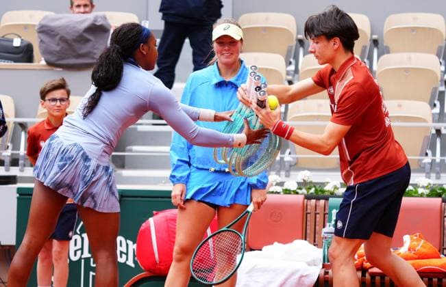 A ballboy delivers racquets to Coco Gauff after she walked onto court with an empty racquet bag as her opponent Olivia Gadecki looks on grinning French Open Tennis, Day Three, Tennis, Roland Garros, Paris, France - 27 May 2025 EDITORIAL USE ONLY No use with unauthorised audio, video, data, fixture lists, club league logos or live services. Online in-match use limited to 120 images, no video emulation. No use in betting, games or single club league player publications.  Copyright: xJavierxGarcia Shutterstockx 15314625aq