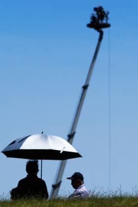 May 31, 2025, Madison, Wisconsin, USA: Two fans seek shelter from the sun under an umbrella while a TV camera crane looms in the background during the third round of the 2025 LPGA, Golf Damen U.S. Womens Open at Erin Hills Golf Course in Erin, Wis. Madison USA - ZUMAb262 20250531_znp_b262_006 Copyright: xJeffxM.xBrownx