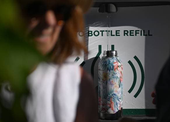 (250701) -- LONDON, July 1, 2025 -- A woman walks past an auto bottle refilling station on the opening day of the Wimbledon Championships in London, Britain, June 30, 2025. Tennis fans faced the hottest start to Wimbledon on record on Monday as temperature soared to 32 degrees Celsius. ) BRITAIN-LONDON-TENNIS-WIMBLEDON-OPENING DAY-WEATHER LixYing 