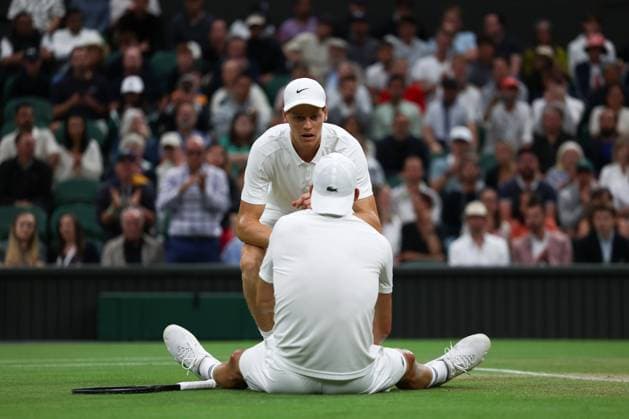 7th July 2025; All England Lawn Tennis and Croquet Club, London, England; Wimbledon Tennis Tournament, Day 8; Grigor Dimitrov (BUL) sits on the court after damaging his pectoral muscle from serving to Jannik Sinner (ITA) as Jannik Sinner (ITA) comes over to help him  ActionPlus12811284 JohnxPatrickxFletcher