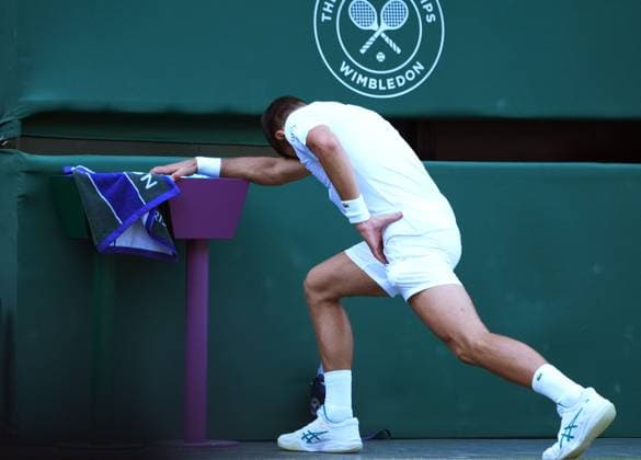 Tennis - 2025 Wimbledon Championships - Men™s singles- Quarter Final - Flavio Cobolli v Novak Djokovic All England Lawn Tennis & Croquet Club - Wednesday 9th July 2025 Novak Djokovic stretches his leg after slipping on the grass 
