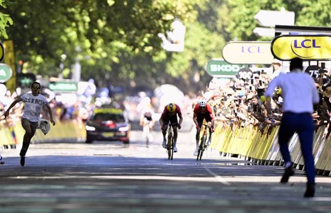 A demonstrator pictured as Norwegian Jonas Abrahamsen of Uno-X Mobility and Swiss Mauro Schmid of Team Jayco AlUla sprint to the finish of stage 11 of the 2025 Tour de France cycling, from and to Toulouse (154km), on Wednesday 16 July 2025 in France. The 112th edition of the Tour de France starts on Saturday 5 July in Lille, France, and will finish in Paris, France on the 27th of July. DIRKxWAEM  x129381085x