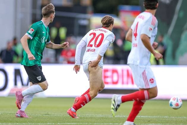 22 08 2025, Football, Preußen Münster 1 FC Nürnberg, 2 Fußball Bundesliga, Preußenstadion, Saison 2025 2026 Caspar Jander 1FC Nuernberg 20 slips his pants during a duel against Joshua Mees Preussen Muenster 08 and pulls half blank Popo Popoblitzer DFB regulations prohibit any use of photographs as image sequences and or quasi video Nordrhein Westfalen Germany