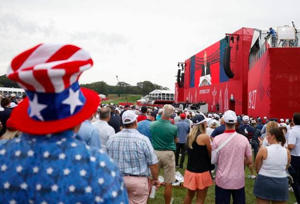 A spectator wears an American flag hat as he listens to Team Europe Ryder captain Luke Donald speak during the opening ceremony for the 45th Ryder Cup at The Black Course at Bethpage State Park in Farmingdale, New York, on Wednesday, September 24, 2025. The three-day golf tournament starts on Friday, September 26, 2025.  RYD20250924840 JOHNxANGELILLO