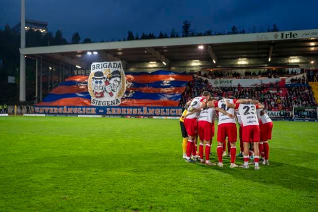 The team of Sportfreunde Siegen swears in the circle before the game In the background you can see the choreo of the fans of Siegen Sportfreunde Siegen VfL Bochum U21 26 09 2025 Soccer, Regionalliga West, 10 Matchday, GER, Siegen, Leimbachstadion Siegen Copyright: HMBxMedia xMarcoxBader