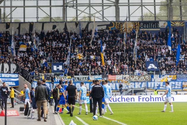 Jena , 270925, Soccer Regionalliga , FC Carl Zeiss Jena vs Chemnitzer FC in the picture Fans Ultras Jena Horda provoke interruption of the game by blocking two escape gates with banners and fans in the block Teams leave the field