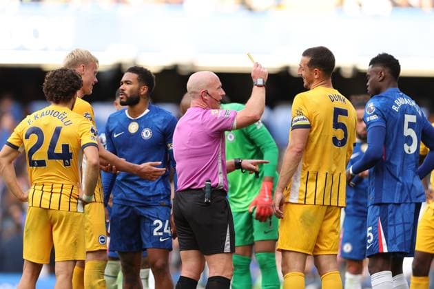 27th September 2025; Stamford Bridge, Chelsea, London, England: Premier League Football, Chelsea versus Brighton and Hove Albion; Referee Simon Hooper giving a yellow card to Benoit Badiashile of Chelsea  JohnxPatrickxFletcher