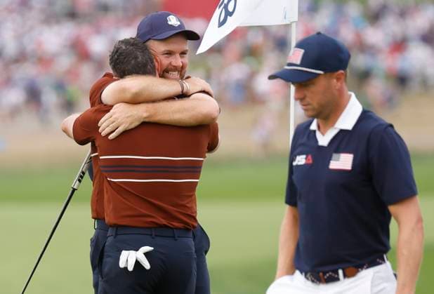 Rory McIlroy and Shane Lowry of Team Europe celebrate after winning their four-ball match against Team United States as Justin Thomas (R) walks off the green on day two of the 45th Ryder Cup at the Bethpage Black Course in Farmingdale, New York on Saturday, September 27, 2025. Europe has a 8.5 to 3.5 lead over the United States after the morning foursome matches on the second day.  RYD20250927642 JOHNxANGELILLO