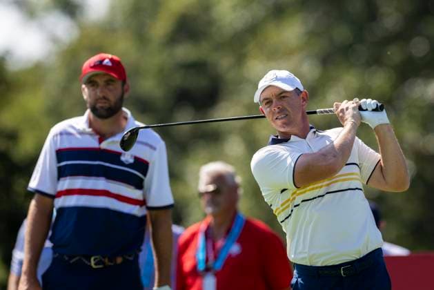 Rory McIlroy of Team Europe drives off the second tee as Scottie Scheffler of Team United States looks on during a singles match on the final day of the 45th Ryder Cup at the Bethpage Black Course in Farmingdale, New York on Sunday, September 28, 2025. Europe has a 12 to 5 lead over the United States going into the final day.  RYD20250928907 COREYxSIPKIN