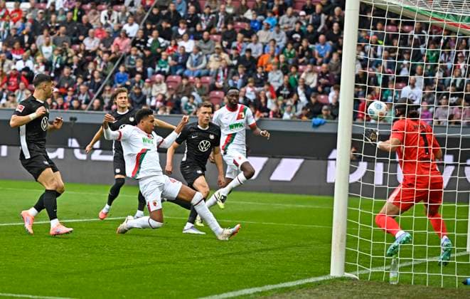 04 10 2025, Soccer 1 Bundesliga 2025 2026, Matchday 6, FC Augsburg VfL Wolfsburg, at WWK Arena Augsburg Noahkai Dominic Banks FC Augsburg scores to make it 1 0 against goalkeeper Kamil Grabara Wolfsburg DFL and DFB regulations prohibit any use of photographs as image sequences and or quasi video