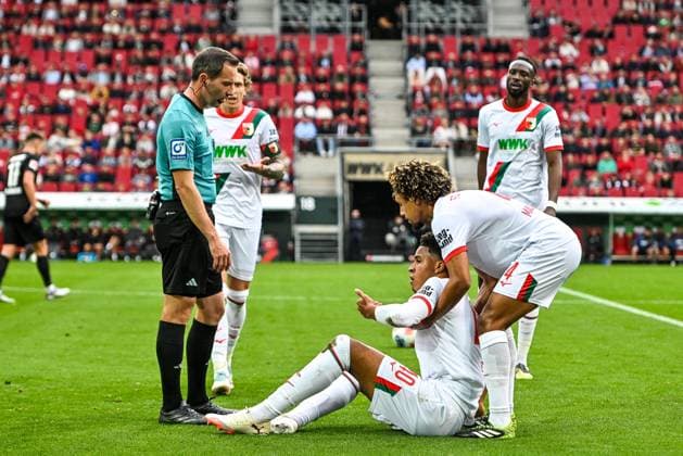 GER, 1 FBL, FC Augsburg vs VfL Wolfsburg 04 10 2025, WWK Arena, Augsburg, GER, 1 FBL, FC Augsburg vs VfL Wolfsburg, in the picture referee Benjamin Brand, Noahkai Banks FC Augsburg, 40 was hit in the face, Han Noah Massengo FC Augsburg, 4 nordphotoxGmbHx xHafner nph00200