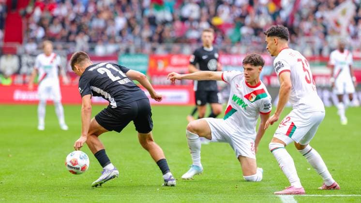 Mert Kömür 36, FC Augsburg , plays the ball while kneeling, Joakim Maehle 21, VfL Wolfsburg and Fabian Rieder 32, FC Augsburg during the match between FC Augsburg v VfL Wolfsburg, Soccer, Men, Bundesliga, 2025 2026, Matchday 6 on 04 10 2025 in Augsburg, WWK Arena DFL and DFB regulations prohibit any use of photographs as image sequences and or quasi video Bayern Germany
