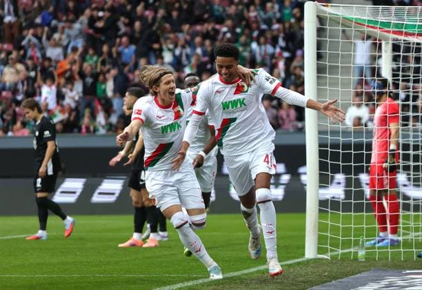 04 10 2025, 1 Bundesliga , FC Augsburg vs VfL Wolfsburg, WWK Arena Augsburg , Football, Sport, im Bild 1 0, Kristijan Jakic FC Augsburg , Noahkai Banks FC Augsburg cheer , Kamil Grabara VfL Wolfsburg beaten