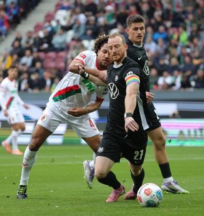 04 10 2025, 1 Bundesliga , FC Augsburg vs VfL Wolfsburg, WWK Arena Augsburg , Soccer, Sports, in the picture Han Noah Massengo FC Augsburg fault Maximilian Arnold VfL Wolfsburg , Joakim Maehle VfL Wolfsburg looks on