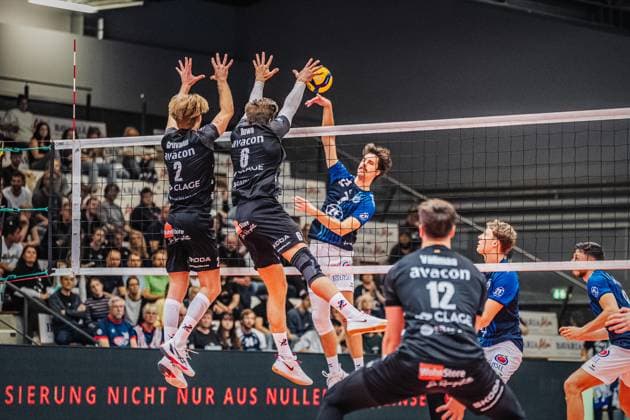 Volleyball mens season 2025 2026 League Cup 2025 VfB Friedrichshafen vs SVG Lüneburg 11 10 2025 Kyle Hobus 7 VfB Friedrichshafen against the block of Daniel Gruvaeus 2 SVG Lüneburg and Jackson Howe 6 SVG Lüneburg