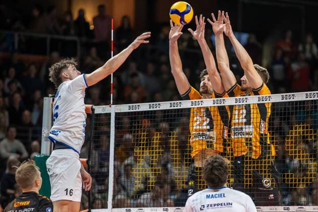 Volleyball Bundesliga, Matchday 1, BR Volleys vs VfB Friedrichshafen at the Max Max Schmeling Halle in Berlin on 21 10 2025 Simon Kohn from VfB Friedrichshafen plays the ball against the block of Jake Hanes BR Volleys and Florian Krage BR Volleys Volleyball Bundesliga, BR Volleys vs VfB Friedrichshafen