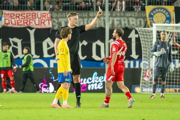 Regionalliga Nordost Season 25 26 Hallescher FC vs 1 FC Lok Leipzig Halle, Germany October 24 2025 In the picture from left Dorian Cevis Leipzig ,Referee Marvin Tennes and Fatlum Elezi Halle Yellow, yellow card, Halle Saale Leuna Chemie Stadion Sachsen Anhalt Germany