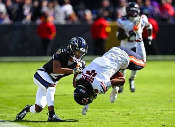 Baltimore Ravens cornerback Nate Wiggins (2) upends Chicago Bears wide receiver Rome Odunze (15) after a first down catch during the first quarter at M&T Bank Stadium in Baltimore, Maryland, on Sunday, October 26, 2025.  BAL20251026115 DAVIDxTULIS
