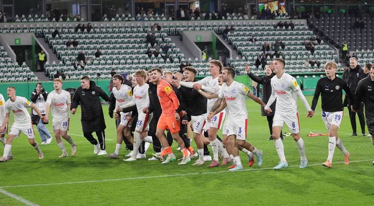 Kiel celebrates victory with the wave Football, Season 2025 2026, Men, Men, DFB Cup, 2nd main round, Volkswagenarena Wolfsburg, VfL Wolfsburg vs Holstein Kiel, 0 1 DFL REGULATIONS PROHIBIT ANY USE OF PHOTOGRAPHS AS IMAGE SEQUENCES AND OR QUASI VIDEO