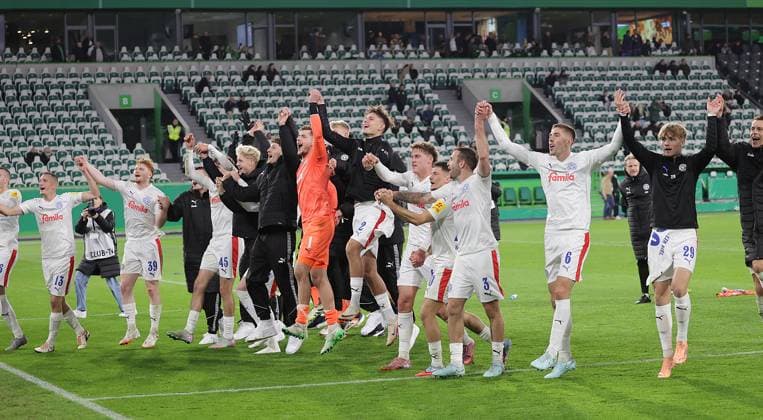 Kiel celebrates victory with the wave Football, Season 2025 2026, Men, Men, DFB Cup, 2nd main round, Volkswagenarena Wolfsburg, VfL Wolfsburg vs Holstein Kiel, 0 1 DFL REGULATIONS PROHIBIT ANY USE OF PHOTOGRAPHS AS IMAGE SEQUENCES AND OR QUASI VIDEO