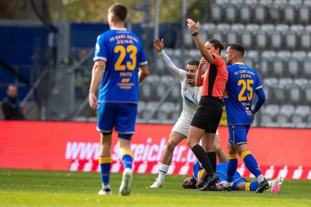 Jena , 311025, Soccer Regionalliga , FC Carl Zeiss Jena vs FC Magdeburg II in the picture Manasse Eshele Jena lies injured on the pitch Andi Hoti Magdeburg with whom he had collided stands next to him
