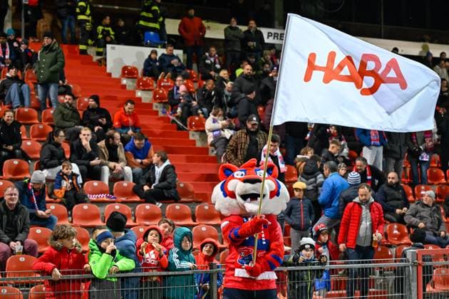 The Unterhaching mascot FONSI with a HABA flag in front of the new family block HABA is now sponsoring 400 free tickets for families in the new family block, 31 10 2025, Unterhaching Germany , Football, Regionalliga Bayern, SpVgg Unterhaching FC Würzburger Kickers xslx