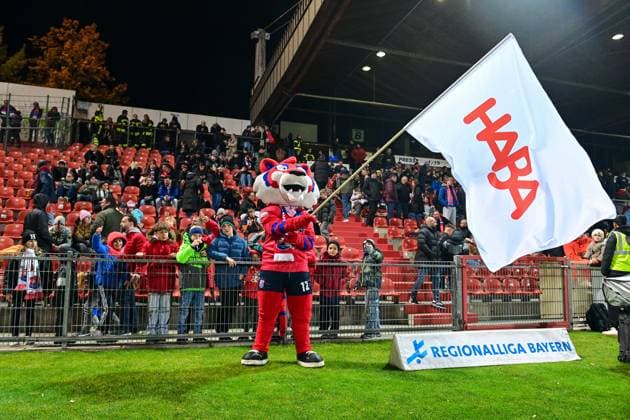 The Unterhaching mascot FONSI with a HABA flag in front of the new family block HABA is now sponsoring 400 free tickets for families in the new family block, 31 10 2025, Unterhaching Germany , Football, Regionalliga Bayern, SpVgg Unterhaching FC Würzburger Kickers xslx