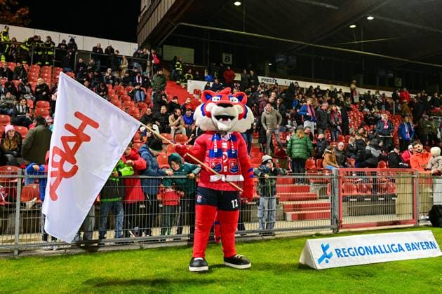 The Unterhaching mascot FONSI with a HABA flag in front of the new family block HABA is now sponsoring 400 free tickets for families in the new family block, 31 10 2025, Unterhaching Germany , Football, Regionalliga Bayern, SpVgg Unterhaching FC Würzburger Kickers xslx