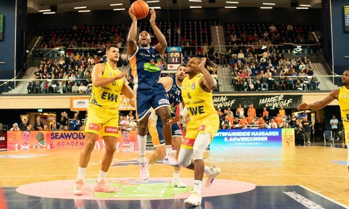 1 11 2025, Basketball, Men, easy credit BBL, easy credit Bundesliga, BBL, Bundesliga, Matchday 6, Rostock Seawolves EWE Baskets Oldenburg Filip Stanic EWE Baskets Oldenburg, left and James Woodard EWE Baskets Oldenburg, right against DeAndre Lansdowne Rostock Seawolves, center Rostock Stadthalle Mecklenburg Vorpommern Germany