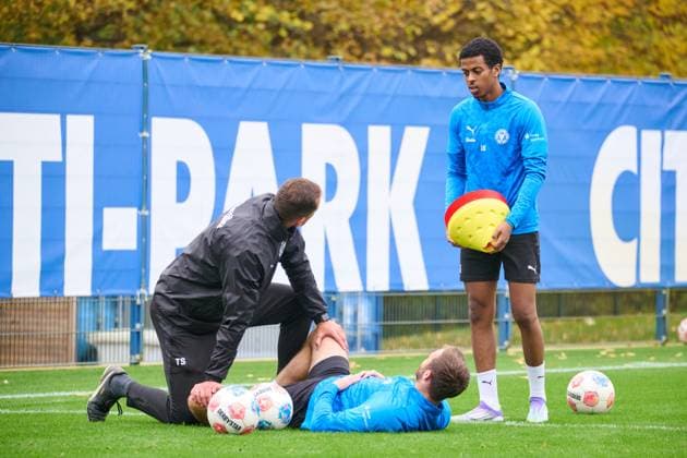 04 11 2025, Football, Men, 2 BL, Season 2025 2026, Training Holstein Kiel Marco Komenda is stretched by athletic trainer Timm Sörensen Andu Kelati behind Kiel, Projensdorf Projensdorf, Training ground, Rase Schleswig Holstein Germany
