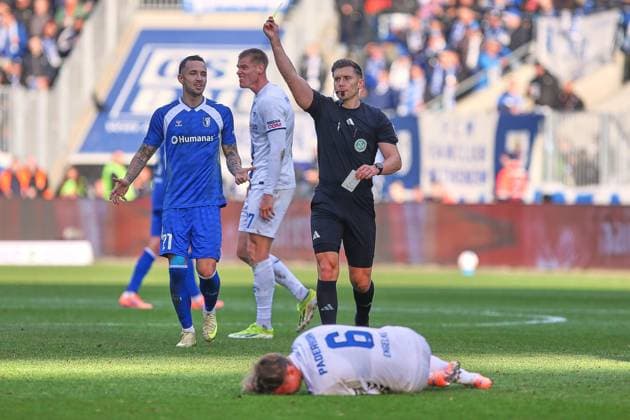 Magdeburg, Saxony-Anhalt, Germany, 09 11 2025 Avnet Arena 12 Matchday, Season 2025 26, 2 Soccer Bundesliga 1 FC Magdeburg SC Paderborn Luis Engelns 06, SC Paderborn 07 lies on the ground while referee Felix Prigan shows the yellow card behind him are Falko Michel 21, 1 FC Magdeburg and Steffen Tigges 27, SC Paderborn 07 Copyright: xdtsxNachrichtenagenturx dts_92834