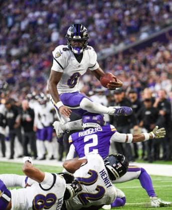 Baltimore Ravens quarterback Lamar Jackson (T) leaps over Minnesota Vikings cornerback Isaiah Rodgers in the fourth quarter against the Minnesota Vikings at U.S. Bank Stadium in Minneapolis, Minnesota on Sunday, November 9, 2025.  MIN20251109108 CRAIGxLASSIG