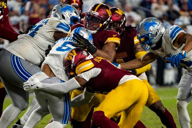 Detroit Lions running back David Montgomery (5) is tackled by cornerback Noah Igbinoghene (6) and other members of the Commanders defense during the third quarter of a game at Northwest Stadium in Landover, Maryland on Sunday, November 9, 2025. The Lions beat the Commanders 44-22.  WAP20251109364 BONNIExCASH