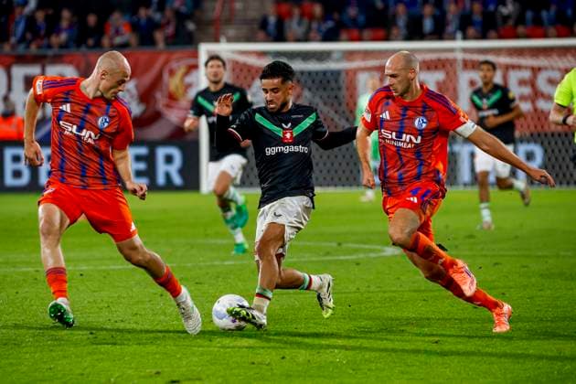Naci Unuvar of FC Twente dribbles with the ball under pressure from Magnus Rosner of Schalke 04 and Henning Matriciani of Schalke 04 FC Twente v FC Schalke 04, 60th Anniversary Game, FC Twente v Schalke 04, De Grolsch Veste Stadium, November 13, 2025, Enschede, Netherlands.