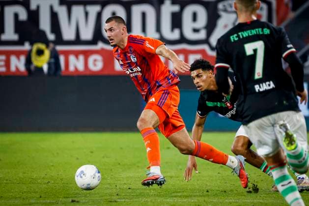 Bojan Potnar of Schalke 04 dribbles with the ball under pressure from Bjorn Titulaer of FC Twente FC Twente v FC Schalke 04, 60th Anniversary Game, FC Twente v Schalke 04, De Grolsch Veste Stadium, November 13, 2025, Enschede, Netherlands.