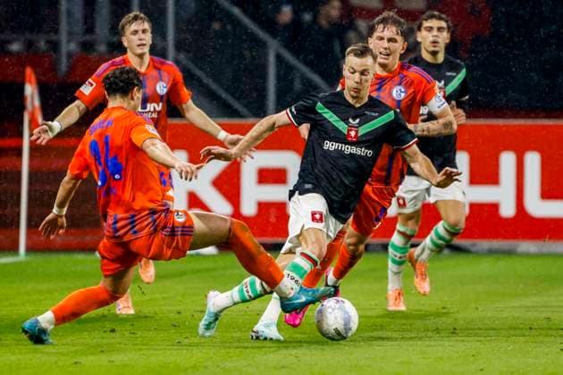 Arno Verschueren of FC Twente dribbles with the ball under pressure from Ayman Emran Gulasi of Schalke 04 FC Twente v FC Schalke 04, 60th Anniversary Game, FC Twente v Schalke 04, De Grolsch Veste Stadium, November 13, 2025, Enschede, Netherlands.