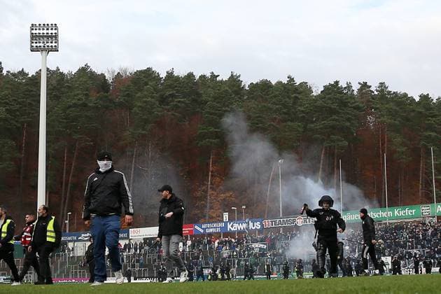 15 11 2025, xrekx, Fußball Regionalliga Suedwest, FC Homburg SV Sandhausen v l Platzsturm SV Sandhausen Fans, Polizei mit Pfefferspray, Homburg Fans verbrennen die geklaute Fahne Banner von Sandhausen DFL DFB REGULATIONS PROHIBIT ANY USE OF PHOTOGRAPHS as IMAGE SEQUENCES and or QUASI VIDEO Homburg