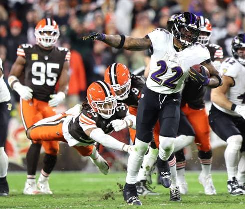 Baltimore Ravens Derrick Henry (22) runs out of the grasp of Cleveland Browns Ronnie Hickman (33) during the third quarter at Huntington Bank Field in Cleveland, Ohio on Sunday, November 16, 2025.  CLE20251116131 AARONxJOSEFCZYK