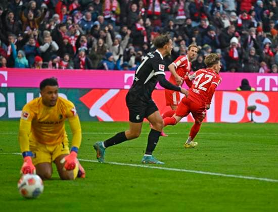 22 11 2025, Soccer Bundesliga 2025 2026, Matchday 11, FC Bayern Munich SC Freiburg, in the Allianz Arena Munich, Lennart Karl FC Bayern Munich scores 1 2 against goalkeeper Noah Atubolu SC Freiburg DFL and DFB regulations prohibit any use of photographs as image sequences and or quasi video