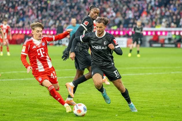 Karl Lennart 42 FC Bayern Muenchen in duel with Max Rosenfelder 37 SC Freiburg , FC Bayern Muenchen SC Freiburg, Soccer, Bundesliga, 11 Matchday, 22 11 2025 DFB regulations prohibit any use of photographs as image sequences and or quasi video Muenchen Bayern Germany Copyright: xkolbert-press UlrichxGamelx