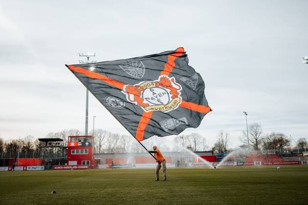22 11 25, Women, Football, Google Pixel Womens Bundesliga, Season 2025 2026, Bayer 04 Leverkusen SGS Essen, Matchday 11 A Leverkusen fan volunteer waves a large flag on the pitch, long shot Leverkusen Ulrich Haberland Stadium NRW Germany