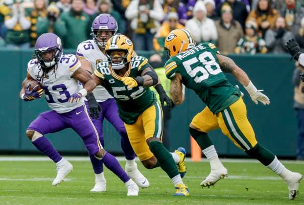 Minnesota Vikings running back Aaron Jones Sr. (L) runs from Green Bay Packers defensive end Rashan Gary (C) and Green Bay Packers linebacker Isaiah McDuffie (R) in the first half of the NFL, American Football Herren, USA game between the Minnesota Vikings and the Green Bay Packers at Lambeau Field in Green Bay, Wisconsin on Monday, November 23, 2025.  MIL20251123805 TANNENxMAURY