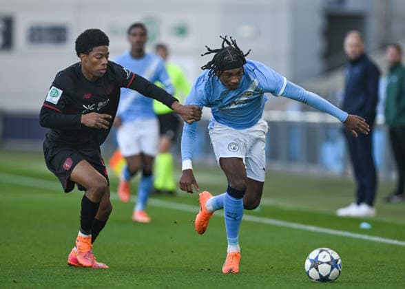 Manchester, England, 25th November 2025. Reigan Heskey of Manchester City holds off a challenge from Nebe Sirak Domnic of Bayer Leverkusen during the Manchester City U19 vs Bayer Leverkusen U19 UEFA Youth League match at the Academy Stadium, Manchester. Picture credit should read: Cody Froggatt Sportimage EDITORIAL USE ONLY. No use with unauthorised audio, video, data, fixture lists, club league logos or live services. Online in-match use limited to 120 images, no video emulation. No use in betting, games or single club league player publications. SPI_004_CF_MANCHESTER_CITY_U19_V_BAYER_LEVERKUSEN_U19 SPI-4326-0004